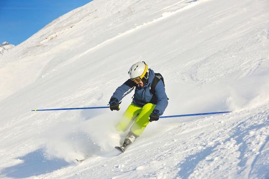 skier skiing downhill on fresh powder snow  with sun and mountains in background