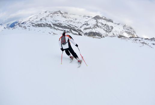 skier skiing downhill on fresh powder snow  with sun and mountains in background