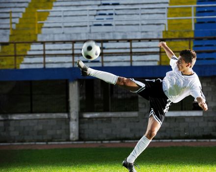 soccer player doing kick with ball on football stadium  field  isolated on black background  in night