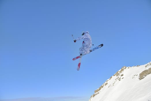 jumping freestyle skier at mountain with fresh snow fresh sunny winter day