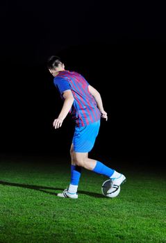 soccer player doing kick with ball on football stadium  field  isolated on black background  in night