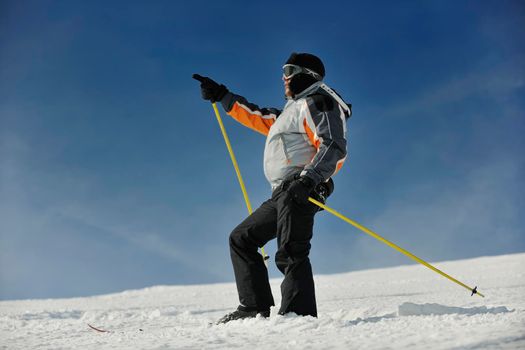 young man pointing direction on winter season during recration ski on mountain with show