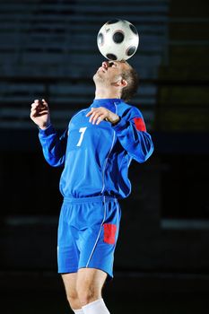 soccer player doing kick with ball on football stadium  field  isolated on black background  in night