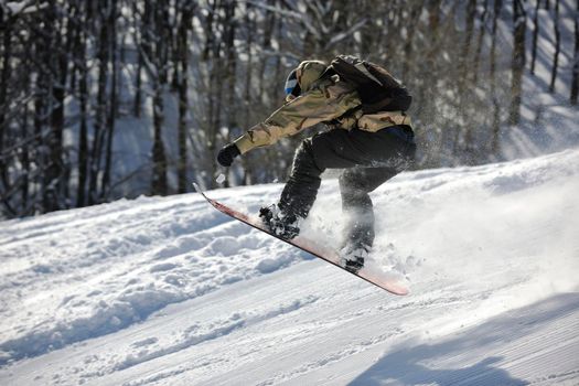 freestyle snowboarder jump and ride free style  at sunny winter day on mountain