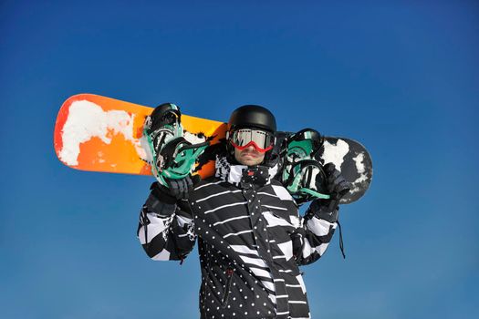 snowboarder relaxing and posing at sunny day on winter season with blue sky in background