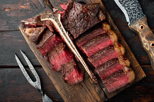 Fresh juicy medium rare Sliced and roast T bone or porterhouse beef meat Steak set, on wooden serving board, on old dark wooden table background, top view flat lay