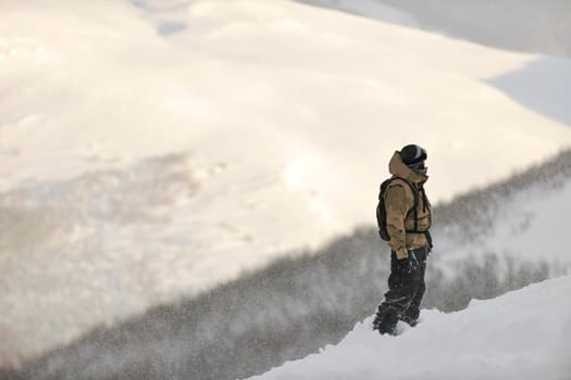 snowboarder relaxing and posing at sunny day on winter season with blue sky in background