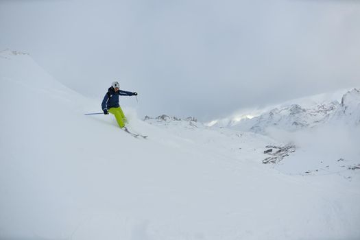 skier skiing downhill on fresh powder snow  with sun and mountains in background