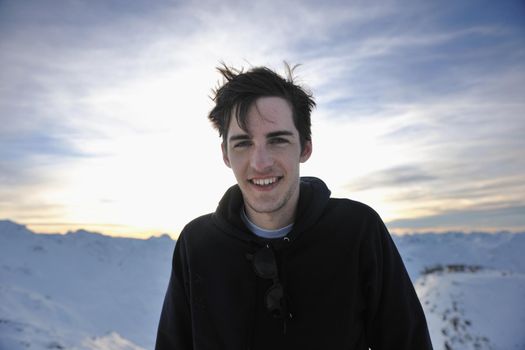 happy young man have fun at  mountain peak on winter season with beautiful sunset 