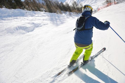 skier skiing downhill on fresh powder snow  with sun and mountains in background