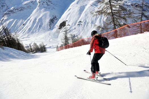 skier skiing downhill on fresh powder snow  with sun and mountains in background