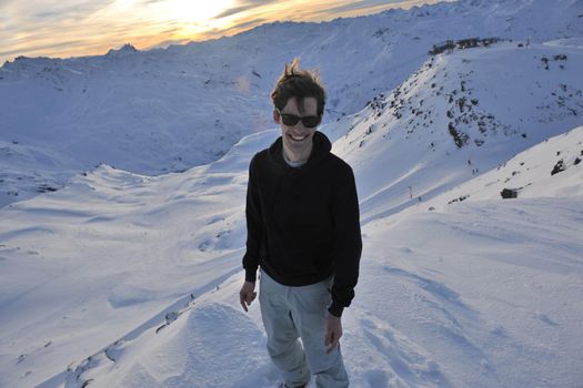 happy young man have fun at  mountain peak on winter season with beautiful sunset 