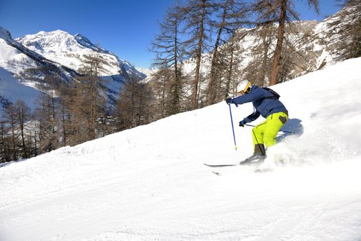 skier skiing downhill on fresh powder snow  with sun and mountains in background