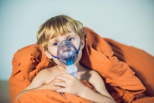 Boy making inhalation with a nebulizer at home.