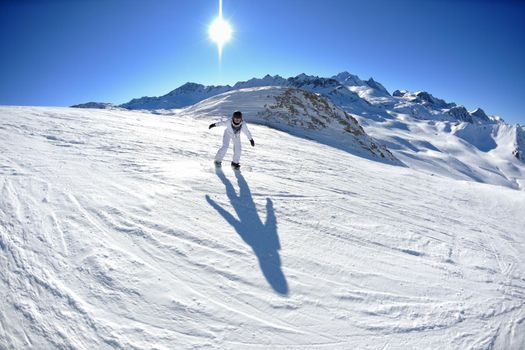 skier skiing downhill on fresh powder snow  with sun and mountains in background