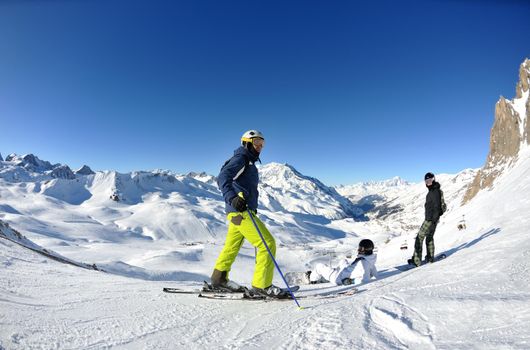 happy people group have fun on ski snow at winter season on mountain with blue sky and fresh air