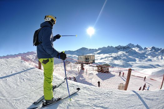 skier skiing downhill on fresh powder snow  with sun and mountains in background