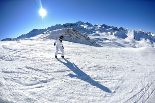 skier skiing downhill on fresh powder snow  with sun and mountains in background