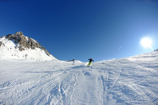 skier skiing downhill on fresh powder snow  with sun and mountains in background