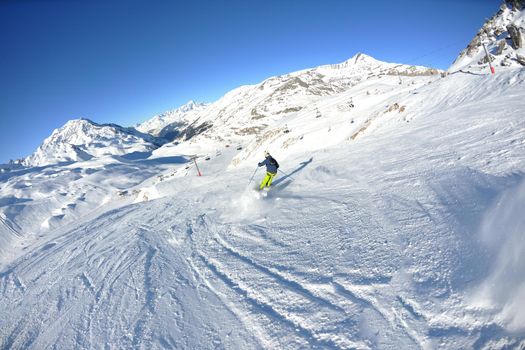 skier skiing downhill on fresh powder snow  with sun and mountains in background