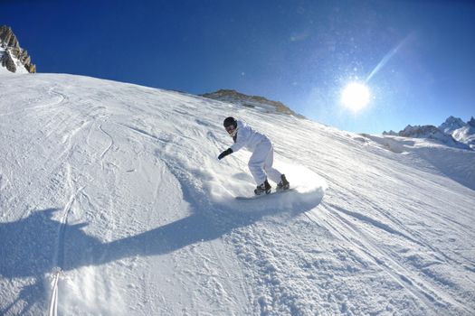 skier skiing downhill on fresh powder snow  with sun and mountains in background