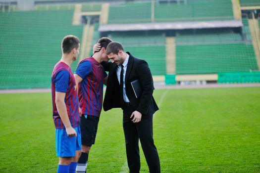 soccer  sport manager in business suit coach and football player on stadium with green grass and white ball