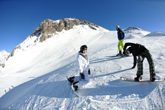 happy people group have fun on snow at winter season on mountain with blue sky and fresh air