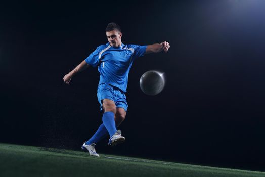 soccer player doing kick with ball on football stadium  field  isolated on black background