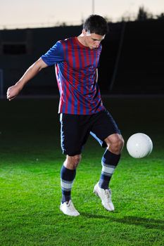 soccer player doing kick with ball on football stadium  field  isolated on black background  in night