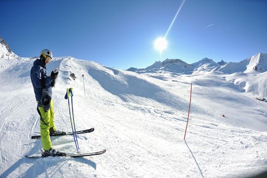 skier skiing downhill on fresh powder snow  with sun and mountains in background