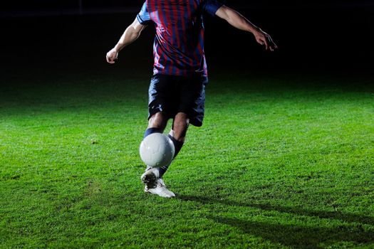 soccer player doing kick with ball on football stadium  field  isolated on black background  in night