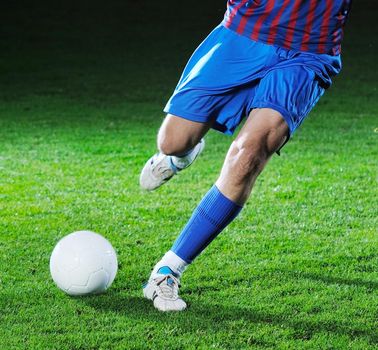 soccer player doing kick with ball on football stadium  field  isolated on black background  in night