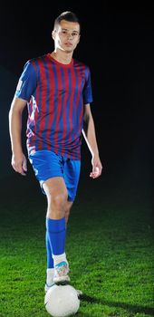 soccer player doing kick with ball on football stadium  field  isolated on black background  in night