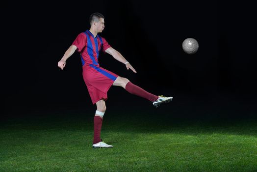 soccer player doing kick with ball on football stadium  field  isolated on black background