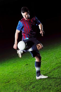 soccer player doing kick with ball on football stadium  field  isolated on black background  in night