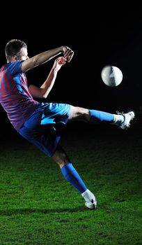 soccer player doing kick with ball on football stadium  field  isolated on black background  in night