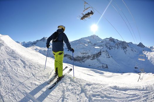 skier skiing downhill on fresh powder snow  with sun and mountains in background