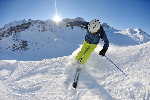 skier skiing downhill on fresh powder snow  with sun and mountains in background