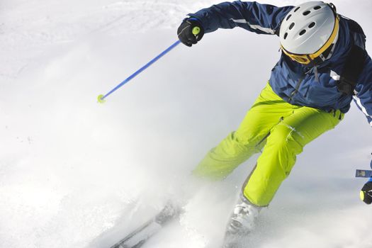 skier skiing downhill on fresh powder snow  with sun and mountains in background