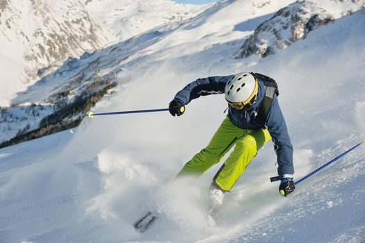 skier skiing downhill on fresh powder snow  with sun and mountains in background