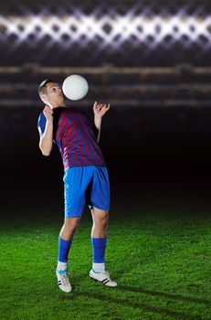 soccer player doing kick with ball on football stadium  field  isolated on black background  in night