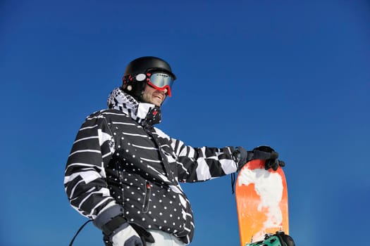 snowboarder relaxing and posing at sunny day on winter season with blue sky in background