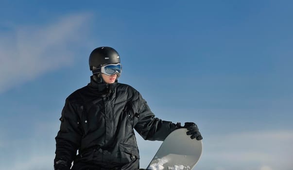 snowboarder relaxing and posing at sunny day on winter season with blue sky in background