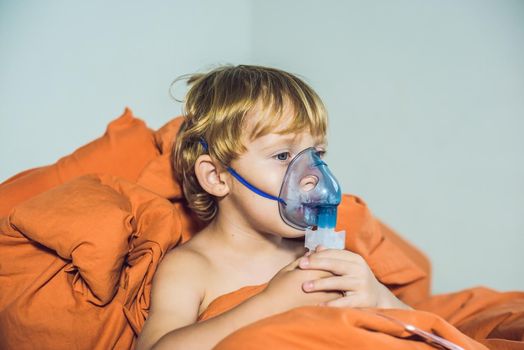 Boy making inhalation with a nebulizer at home.