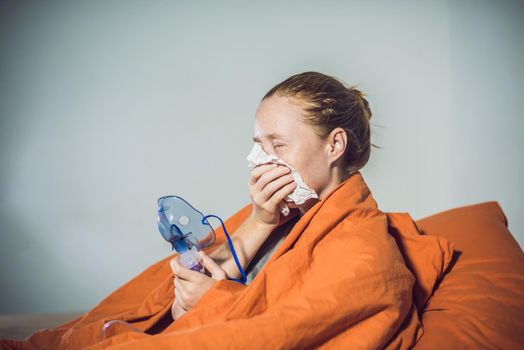 Woman with flu or cold symptoms making inhalation with nebulizer - medical inhalation therapy.