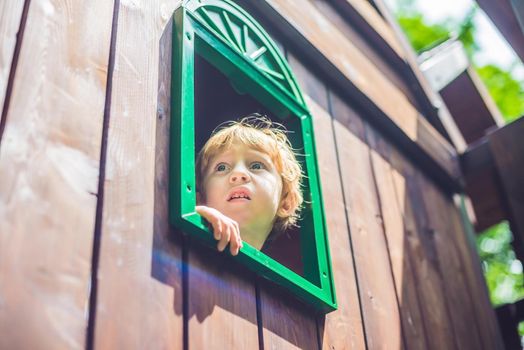 Cute little boy is playing on a wooden playground.