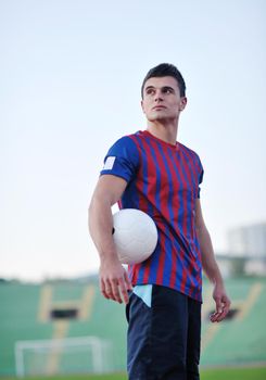 portrait of young handsome soccer player man at football stadium and green grass