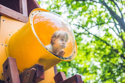 Cute little boy is playing on a wooden playground.