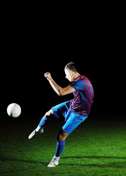 soccer player doing kick with ball on football stadium  field  isolated on black background  in night