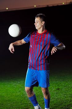 soccer player doing kick with ball on football stadium  field  isolated on black background  in night